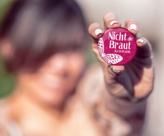 Frau mit JGA Button Nr. 8 in der Hand